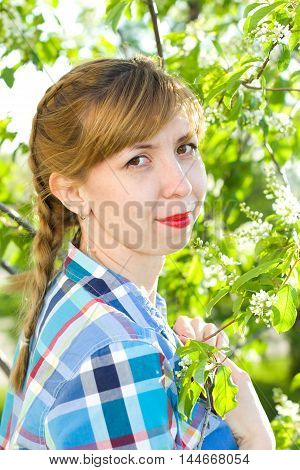 Portrait of a girl with a bird-cherry tree in the spring