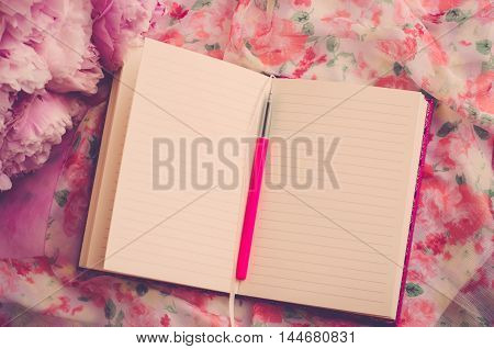 Open notebook and pen on a beautiful pink flower background (vintage)