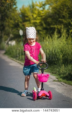 adorable little girl on a scooter in the street