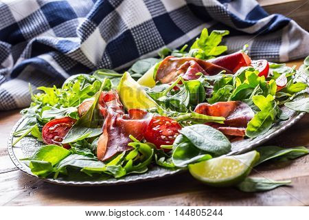 Dried beef bresaola. Salad bresaola arugula baby spinach tomatoes lime and cheese parmesan.