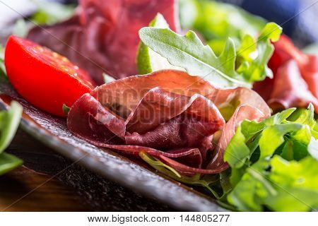 Dried beef bresaola. Salad bresaola arugula baby spinach tomatoes lime and cheese parmesan.