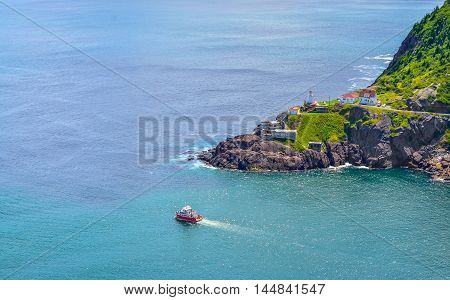 Boats motor past Fort Amherst.  Rugged coastline and Atlantic ocean. Warm summer day in August with views from atop the Historically famous Signal Hill in St. John's.