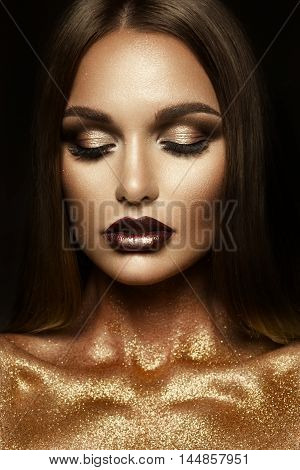 Beautyful girl with gold glitter on her face and body