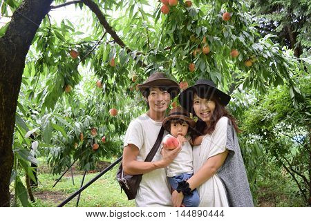 Young Family Is Smiling At Peach Orchard