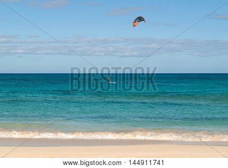 Unknown kitesurfer surfing on a flat azure water of Atlantic ocean in Corralejo Fuerteventura Canary islands Spain