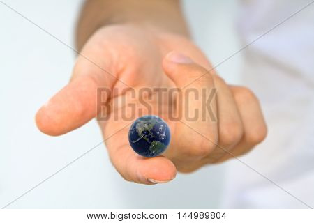 Hand holding earth on fingertip/ World at your Fingertips