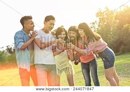Asian people look something at cellphone with his friends in the park