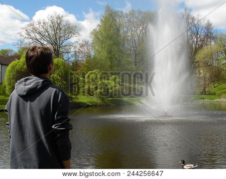 Latvia Madona. The Boy Looks At The Fountain In The Park.