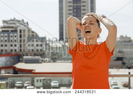 Young Woman In A Red Dress Holding On To The Head On The Background Of The City, Concept, Problems, 