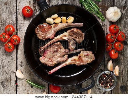 Roasted Lamb Ribs With Rosemary, Tomatoes And Garlic On Pan On A Dark Old Rustic Wooden Background, 