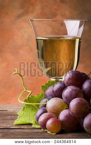 On Rustic Wooden Table Bunch Of Red Grapes On The Wine Glass Background