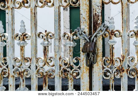 Rusty Iron Door With Padlock Attached To A Chain, Closing The Door. Iron Door Worked With Details. P