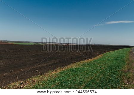 Plowed Field On Which Agricultural Machinery Rides. Summer Day Two Tractors To Plow, Plow The Soil O