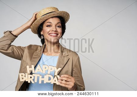 Beautiful Playful Smiling Mixed Race Woman Wearing Canotier Straw Hat Holding Happy Birthday Text Lo
