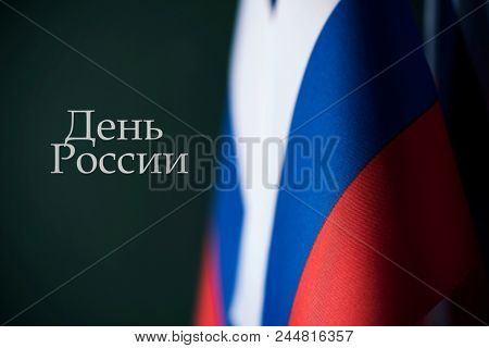closeup of some russian flags and the text ârussia dayâ written in russian against a dark green background