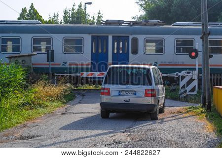 Rovigo, Italy - June, 9, 2018: closed railroad crossing gate and waiting car in Rovigo, Italy
