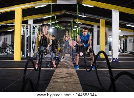 young fit sports couple working out in functional training gym doing  battle ropes cross fitness exercise