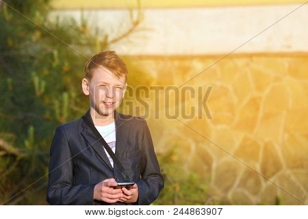 A Boy With A Smartphone Reads A Message In The Smartphone And Looks At The Camera.