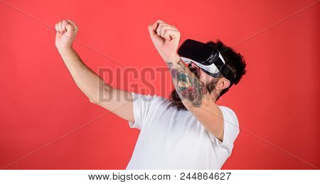 Man With Beard In Vr Glasses Driving Motorbike, Red Background. Virtual Driving Lessons Concept. Hip