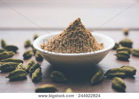 Elaichi Or Cardamom Powder In Bowl Or Heap Over Moody Background With Pods. Selective Focus