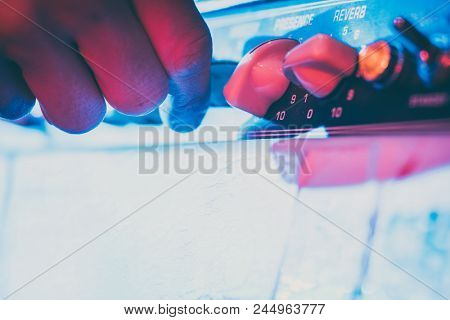 Musician turning the volume on amp up to make the music louder