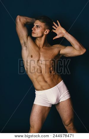 Athlete With Confident Face Wearing White Underwear. Man With Naked Torso On Dark Green Background. 