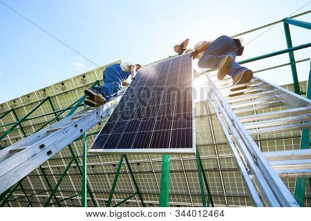 Solar Battery Screen Installing By Two Mounters. Standing On Ladders, Mounting On Metallic Construct