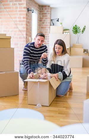 Beautiful famiily, kid playing with his parents riding cardboard fanny box at new home