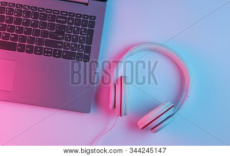 Gaming Equipmen. Laptop And Headphone With Neon Gradient Pink-blue Light. Music Concept. Computer Ga