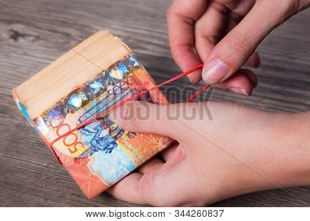 Hands Holding A Wad Of Money With An Elastic Band. Tenge Kzt. National Currency Of Kazakhstan, Kz. E