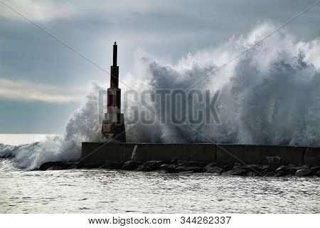 Giant Waves Breaking On The Breakwater And The Lighthouse On Aguda Beach, Miramar, Arcozelos Town