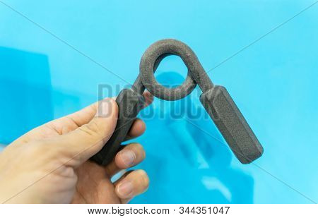 hand with fitness hand gripper printed on 3d printer close-up.
