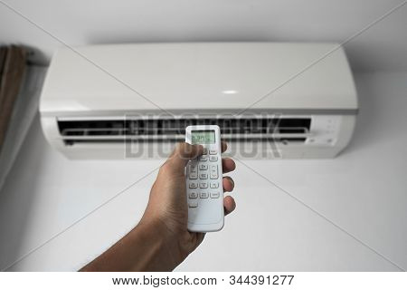 Mans Hand Using Remote Controler. Hand Holding Rc And Adjusting Temperature Of Air Conditioner Mount