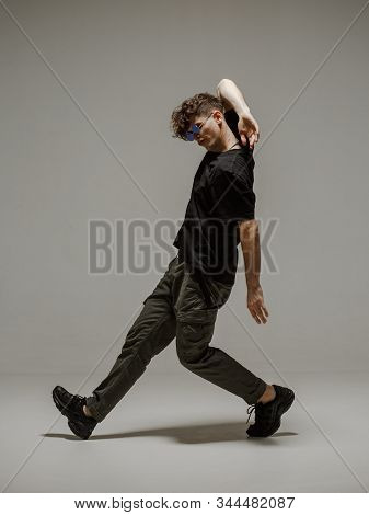 Guy Dancing Contemporary Dance In Studio. Neutral Grey Background. Acrobatic Bboy Dancer.