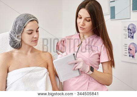 Woman Wearing Dosposable Medical Cap Being At Consultation In Cosmetology Clinic. Attractive Female 
