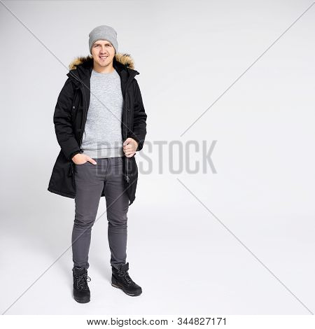 Fell Length Portrait Of Young Handsome Man Posing In Warm Winter Clothes Over Gray Background With C