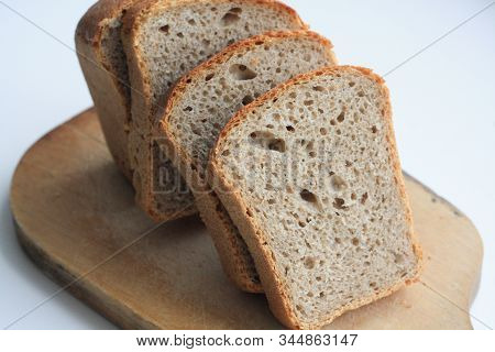 Sliced Black Bread On A Wooden Board On A White Background
