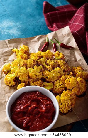 Vertical Baked Cauliflower On Kraft Paper With Tomato Sauce And Chili Peppers Blue Background