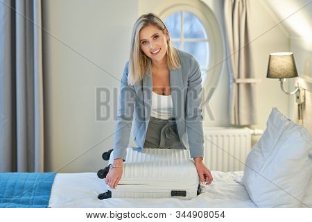 Businesswoman unpacking suitcase in hotel room