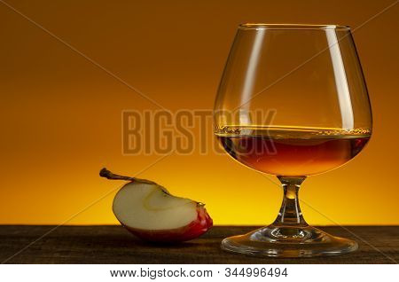 Glass Of Calvados Brandy And Red Apples On Wooden Table