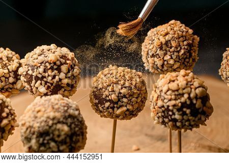 Chocolate Cake Pops With Hazelnut And Golden Flakes On A Wooden Stick