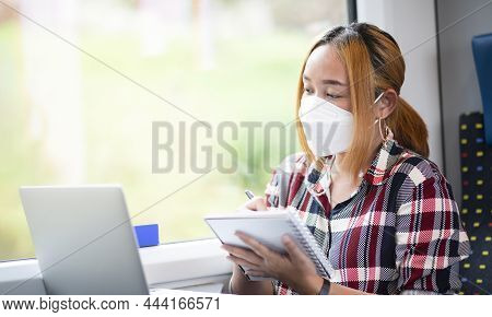 Businesswoman Wearing A Mask And Working On Laptop On A Train, Asian Freelance Writer Or Designer Wr