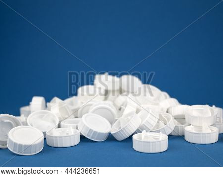 Pile Of White Plastic Screw Caps On The Blue Background, Selective Focus. Closures Made From Renewab
