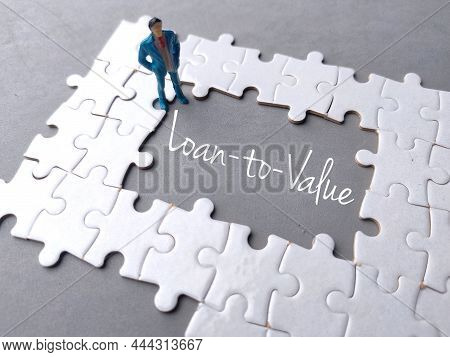 Text Loan To Value Written On Gray Background With White Puzzle And Miniature People.