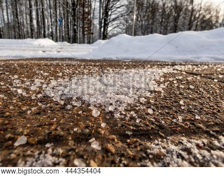 Salt Grains On Icy Sidewalk Surface In The Winter. Applying Salt To Keep Roads Clear And People Safe