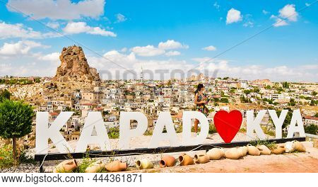 Caucasian Female Tourist Stand By Kapadokya Billboard With Ortahisar Castle Landscape In Cappadocia 