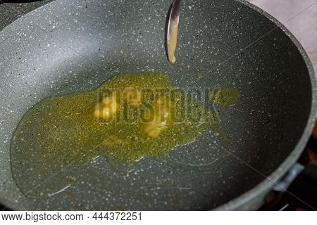 Spoon Adding Butter To Vegetable Oil On Empty Preheated Skillet.