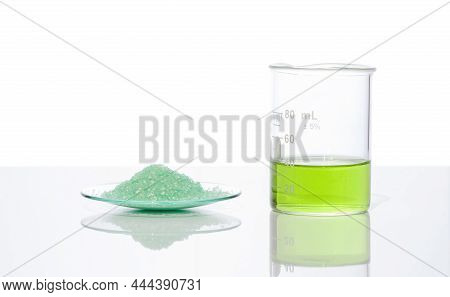 Ferrous Sulfate In Chemical Watch Glass Place Next To Iron (ii) Sulfate Liquid In Beaker. Close Up C