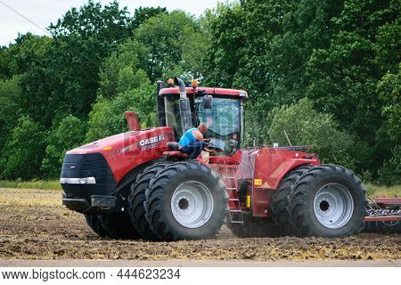 Tractor Driver Near A Large Red Tractor. A Farmer On A Tractor Prepares Land For A Seeding, Tractor 