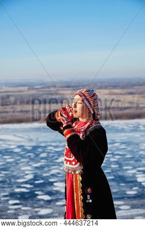 Side View Of Woman In Authentic Costume Is Playing A Musical Instrument Jew's Harp With The Frozen R